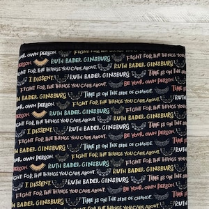 May include: Black fabric with a repeating pattern of the text "Ruth Bader Ginsburg" and quotes from her, including "Fight for the things you care about." and "Time is on the side of change."