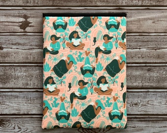 Puede incluir: Una funda para portátil rosa con un patrón repetido de mujeres leyendo libros en un jardín. Las mujeres están ilustradas en tonos de verde, marrón y azul. El fondo es rosa claro con plantas y flores verdes.