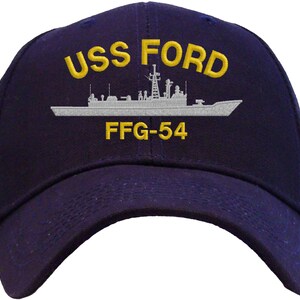 May include: Navy blue baseball cap with the text "USS FORD" in yellow, along with a gray illustration of a ship and the text "FFG-54". The cap has a curved brim.