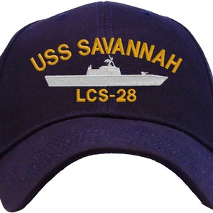 May include: A navy blue baseball cap with an embroidered white ship and the text "USS SAVANNAH LCS-28" in gold.
