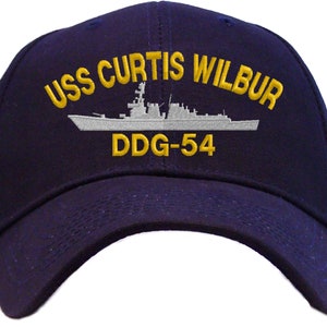 May include: A navy blue baseball cap with an embroidered white ship and the text "USS CURTIS WILBUR DDG-54" in gold.