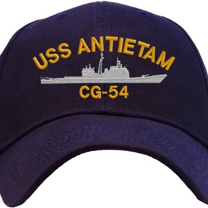 May include: A navy blue baseball cap with a white embroidered ship and the text "USS ANTIETAM CG-54" in gold.