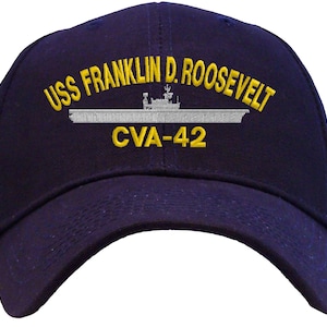 May include: Navy blue baseball cap with the text "USS FRANKLIN D. ROOSEVELT CVA-42" embroidered in yellow and white. The cap features a curved brim and a structured crown, suitable for casual wear.