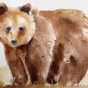 May include: Watercolor painting of a brown bear standing on a light brown background. The bear is looking directly at the viewer with its mouth closed. The bear's fur is painted with a light brown wash and has darker brown accents.