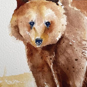 May include: Watercolor painting of a brown bear with black eyes and a black nose. The bear is looking directly at the viewer. The background is a light brown.