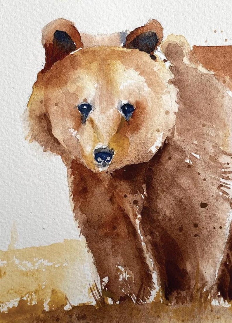 May include: Watercolor painting of a brown bear with black eyes and a black nose. The bear is looking directly at the viewer. The background is a light brown.