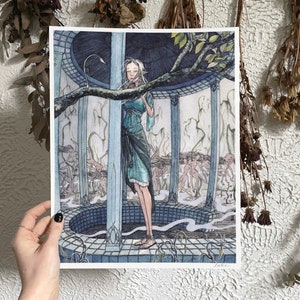 Peut inclure: Une estampe artistique représentant une figure en robe turquoise dans une structure circulaire avec des piliers. L'illustration a un thème fantastique, avec d'autres personnages en arrière-plan et une branche d'arbre au-dessus.