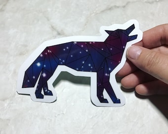 May include: A geometric wolf silhouette sticker with a galaxy design. The wolf is outlined in black and filled with a gradient of purple and blue with white stars.