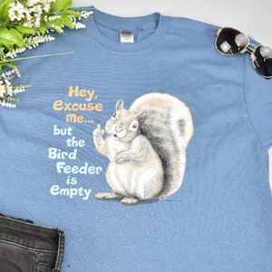 May include: A blue t-shirt with a squirrel graphic and the text "Hey, Excuse Me... but the Bird Feeder is Empty".