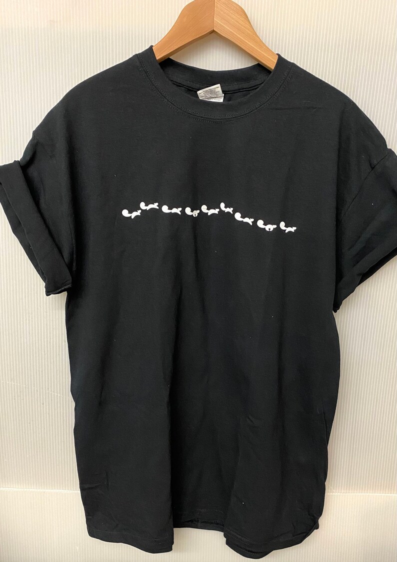May include: Black t-shirt with a white graphic of a line of small white figures.
