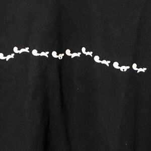 May include: Black t-shirt with a white design of a line of small animals running across the front.