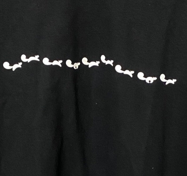 May include: Black t-shirt with a white design of a line of small animals running across the front.