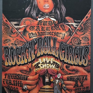 Könnte beinhalten: Plakat für die Rock 'N' Roll Circus Live Show. Das Kunstwerk zeigt eine Frau mit Tätowierungen und Teufelshörnern. Der Text enthält "Rude Gallery 10th Anniversary" und Veranstaltungsdetails: Donnerstag, 11. Februar 2010, Shibuya AX, Öffnung 14:00 Uhr, Beginn 15:00 Uhr.
