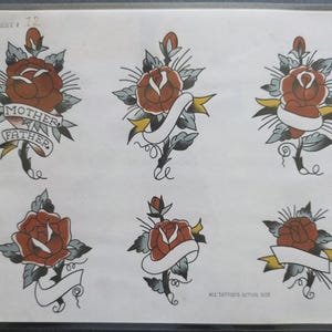 Pode incluir: Uma folha de desenhos de tatuagem marcada como SHEET # 12 apresentando seis ilustrações de rosas vermelhas com folhas e caules verdes. Cinco designs incluem faixas brancas em branco com detalhes amarelos, uma faixa contém o texto MOTHER FATHER.
