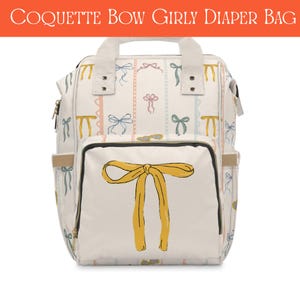 Może przedstawiać: Kremowa torba na pieluchy ze wzorem kokardki i napisem "Coquette Bow Girly Diaper Bag". Torba posiada dużą żółtą kokardę na przedniej kieszeni i mniejsze kokardki w różnych kolorach. Ma wiele kieszeni i górny uchwyt.