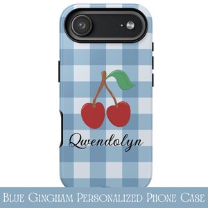 May include: A phone case featuring a light and medium blue gingham check pattern. The design includes a pair of red cherries with a green leaf on brown stems. The name Qwendolyn is printed in a black cursive script font below the cherries.