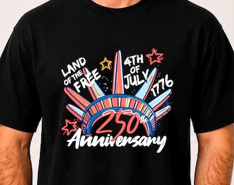 May include: Black t-shirt with a colorful graphic celebrating the 250th anniversary of the 4th of July. The design includes the text "Land of the Free" and "4th of July 1776". The shirt is worn by a person.