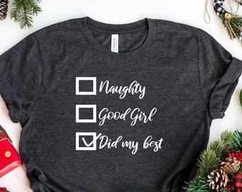 May include: A dark gray t-shirt with a white graphic that says "Naughty, Good Girl, Did my best" with checkboxes next to each option. The checkbox next to "Did my best" is checked.