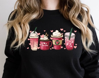 Puede incluir: Sudadera negra con un gráfico de cuatro bebidas de café diferentes con crema batida y corazones. El texto "Fine Love" está en una de las tazas.