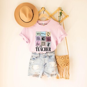May include: Pink t-shirt with a graphic of school supplies in colorful squares and the text "In My Teacher Era".