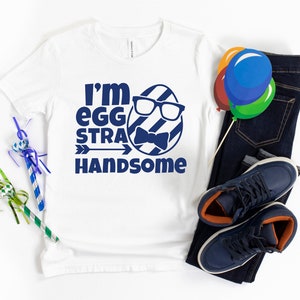 May include: White t-shirt with a blue graphic of an egg wearing glasses and a bow tie. The text "I'm egg-stra handsome" is printed below the egg.