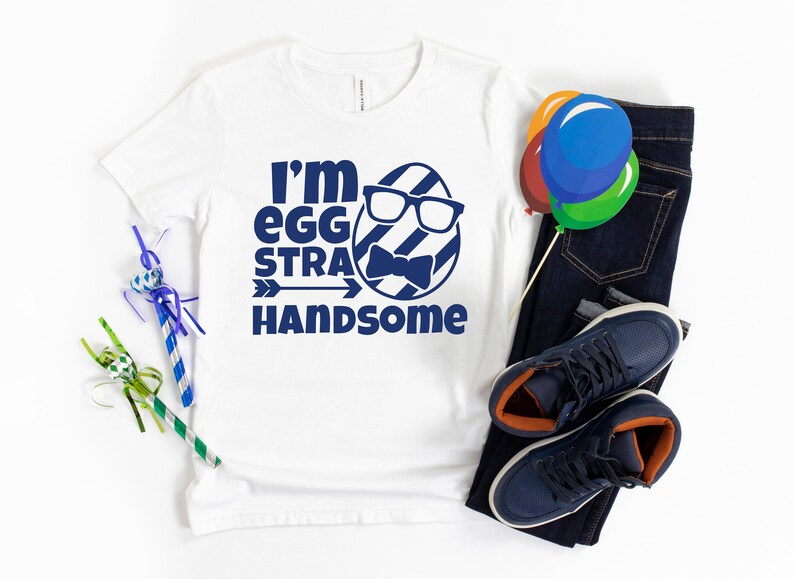 May include: White t-shirt with a blue graphic of an egg wearing glasses and a bow tie. The text "I'm egg-stra handsome" is printed below the egg.