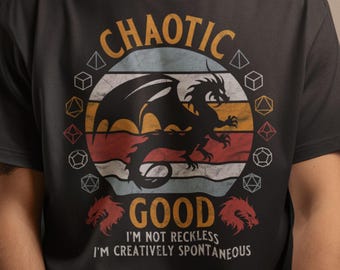 Może przedstawiać: Czarny T-shirt z grafiką w stylu vintage przedstawiającą smoka i kostki do gry. Tekst "CHAOTIC GOOD" jest nadrukowany na biało, a pod nim znajduje się napis "I'M NOT RECKLESS I'M CREATIVELY SPONTANEOUS".