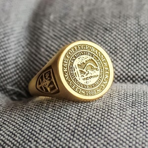 May include: A gold class ring with the inscription "Yale College 1701" and a crest featuring a tree and a bird.