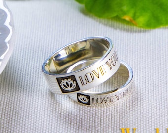 May include: Two silver rings with the inscription "I love you" and a lotus flower design. The rings are on a white surface with a white saucer and green leaves in the background. The UPS logo and the text "Worldwide Fast Shipping" are visible in the lower right corner of the image.