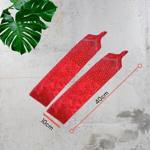 K&ouml;nnte beinhalten: Zwei rote Satin-Armw&auml;rmer mit glitzerndem Design. Die Armw&auml;rmer sind 40 cm lang und 10 cm breit.