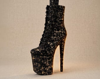 Op de afbeelding: Een zwarte enkelboot met een hoog plateau en een dunne stilettohak. De laars heeft een vetersluiting aan de voorzijde met zwarte veters en is bedekt met een herhalend patroon van kleine, lichtgekleurde, vierpuntige sterren over het oppervlak.