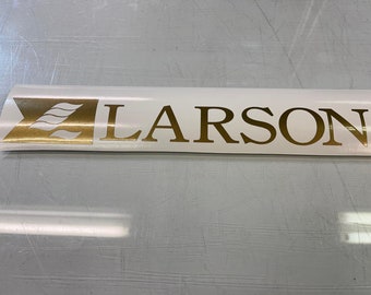 May include: Gold decal with a stylized wave design and the word "LARSON" in a serif font.