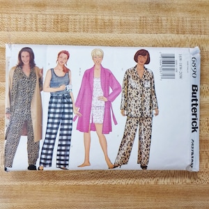 May include: A sewing pattern package for pajamas and a robe. The pattern is from the brand Butterick and has the number 6890. The pattern shows four different styles of pajamas and a robe, including a leopard print, a plaid print, and a floral print.