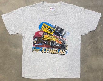 May include: Grey t-shirt featuring a colourful illustration of a race car driver, a yellow racing car, and the text "Daryl Stimling".