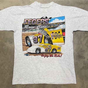 May include: A gray t-shirt with a yellow and white race car graphic. The car has the number 97 on it and the text "Fegers Race Cars" and "Enjoy the Ride!" are printed on the shirt.