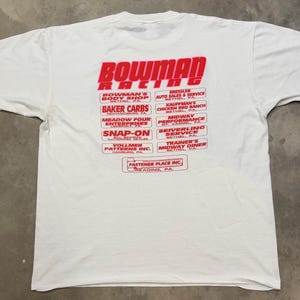Puede incluir: Camiseta blanca con el texto rojo "BOWMAN RACING" y varios nombres de empresas. La camiseta tiene mangas cortas y cuello redondo. La camiseta est&aacute; hecha de un material suave y c&oacute;modo.