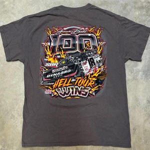 May include: A dark gray t-shirt with a graphic of a race car with flames and the text "Shane Ball 100 Hell Tour Wins".