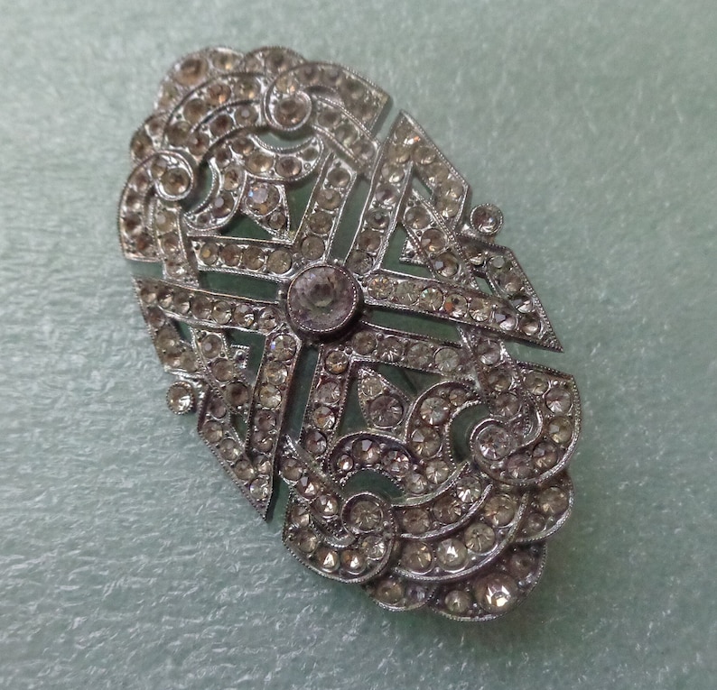 Silberfarbene ovale Brosche mit Pave besetzt mit klarem Strass und mit Posamentverschluss Bild 5