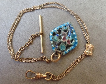 Puede incluir: Un porta-reloj de cadena de oro con un colgante de esmalte azul y blanco con un diseño floral. El colgante tiene una flor rosa y hojas azules.