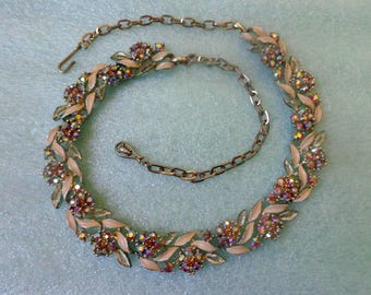 May include: Vintage necklace featuring a floral design with iridescent rhinestones and pale pink enamel leaves. The necklace has a gold-tone chain and clasp, creating a classic and elegant look. A beautiful piece of jewelry for special occasions.