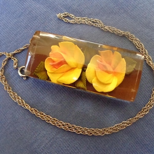 Lucite pendant with embedded flowers on a silver tone chain