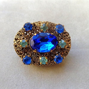 Ornate filigree brooch with blue glass stones