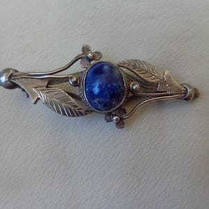 Handcrafted silver brooch with blue gemstone cabochon