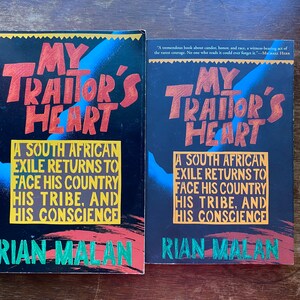 May include: Two copies of the book "My Traitor's Heart" by Rian Malan. The book cover is black with a yellow, red, and blue abstract design. The title is in large, red, stylized letters. The subtitle is "A South African Exile Returns to Face His Country, His Tribe, and His Conscience".