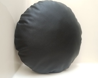 May include: A round black leather cushion with a textured surface.