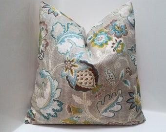May include: A decorative throw pillow with a floral pattern in shades of brown, teal, and white on a beige background.