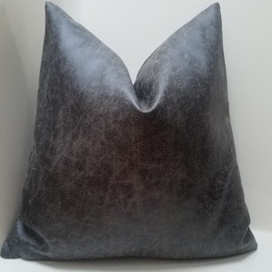 May include: A gray faux leather pillow with a textured surface.