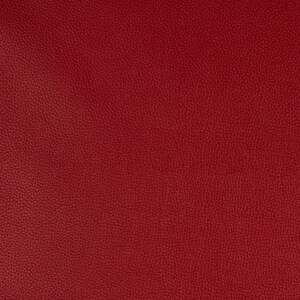 May include: A close-up of a deep red textured fabric. The fabric has a pebbled surface and a rich, solid color.