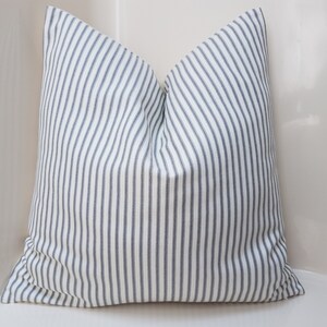 Puede incluir: Una almohada blanca con rayas azules. La almohada est&aacute; hecha de una tela suave y tejida y tiene un dise&ntilde;o simple y cl&aacute;sico.