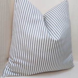 Puede incluir: Una almohada blanca con rayas azules. La almohada est&aacute; hecha de una tela suave y tejida y tiene un dise&ntilde;o simple y cl&aacute;sico.